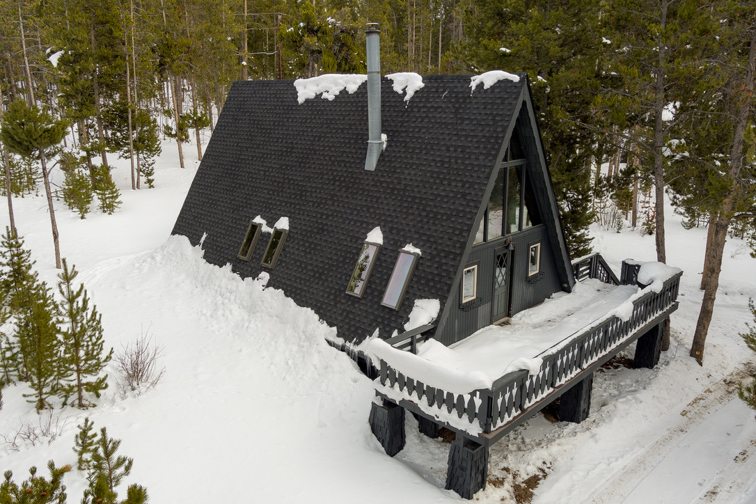 The A-frame's roofline and deck under deep snow.