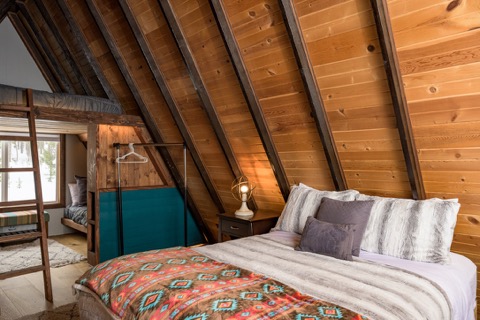 A queen bed under the sloped wood-beamed ceiling.