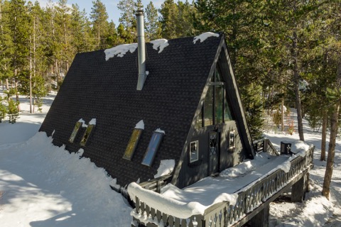 The A-frame's roofline and chimney against blue sky.