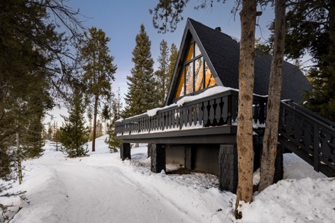The A-frame glowing at dusk over snow.