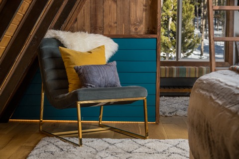 An accent chair with pillows beside the bed.
