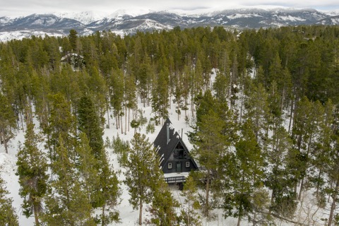 The A-frame alone in a sea of pines.