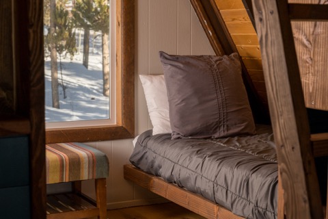 A single bed nook beside a snowy window.