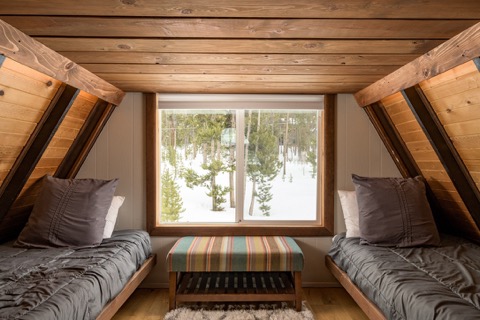 Twin beds flank a window under sloped ceiling.