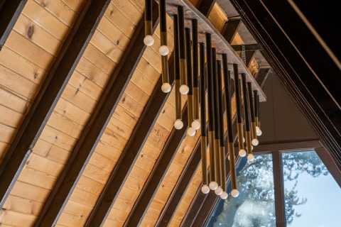 A modern light fixture along the beamed ceiling.