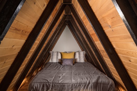 The loft bed centered beneath the A-frame's peak.
