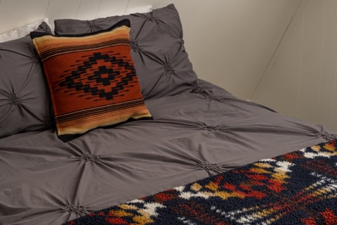 A patterned throw pillow on the gray bedding.