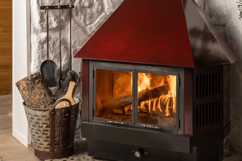 The wood stove burning with logs stacked nearby.