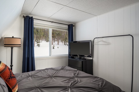 The bedroom's TV corner and clothing rack.