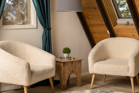 Two boucle armchairs by a carved side table.